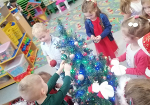 Dzieci ubierają świąteczną choinkę.